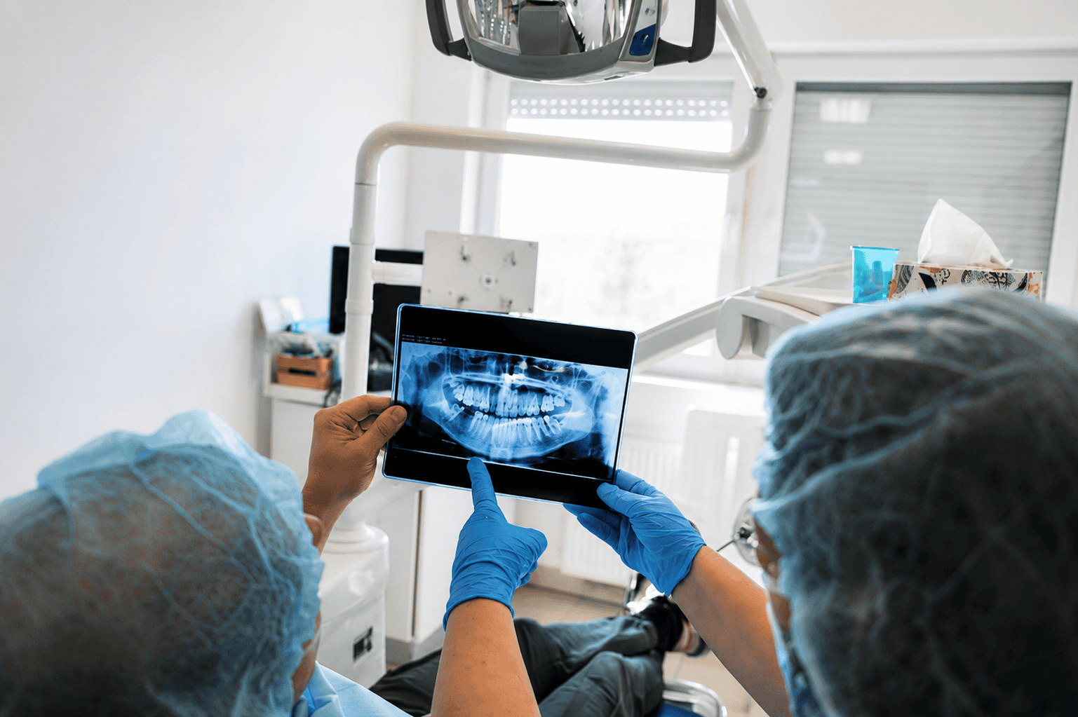 Professionisti dentali che esaminano una radiografia di un paziente in un contesto clinico.