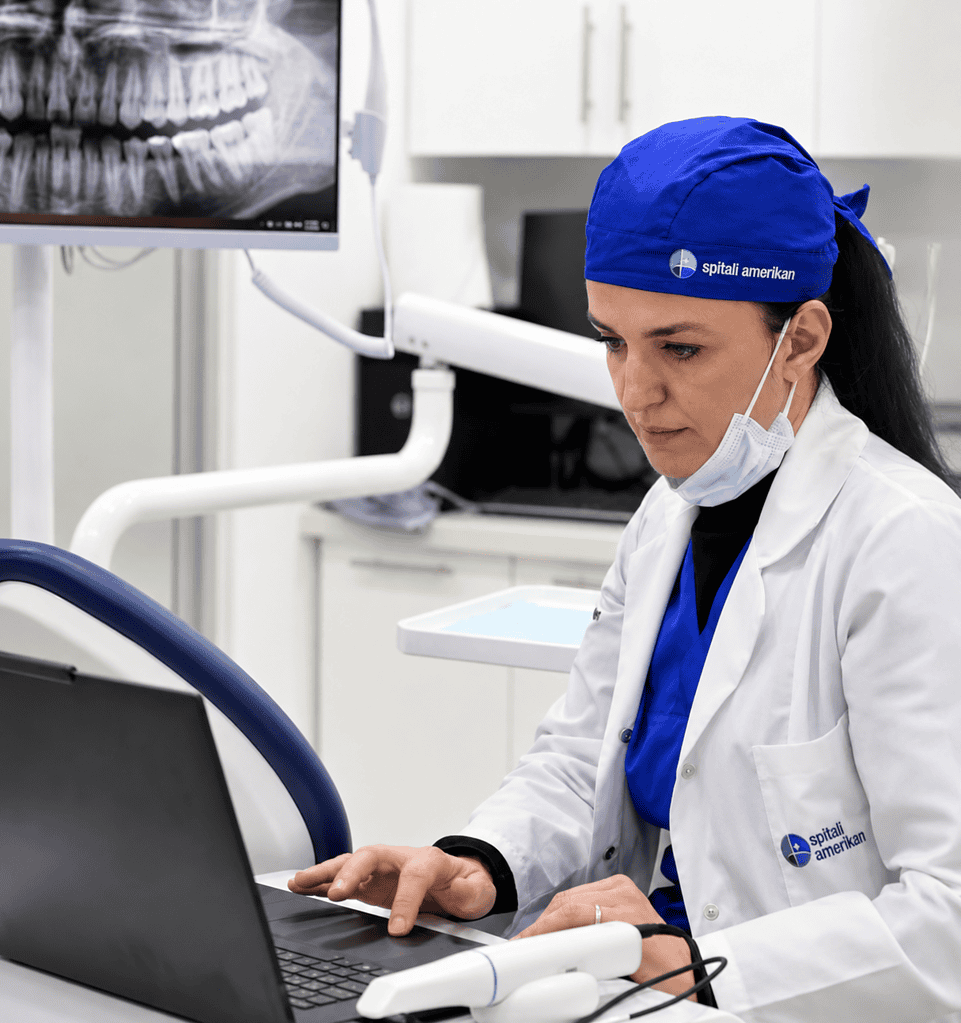 Dental professional reviewing patient X-ray on computer in clinic.
