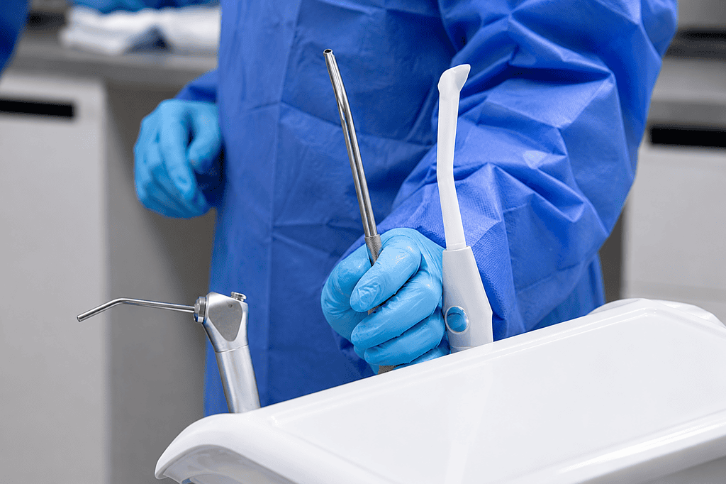 Dental professional holding dental tools in a clinical setting.