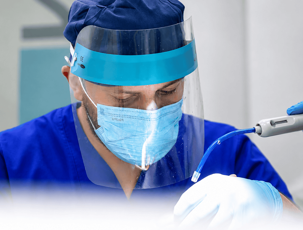 Healthcare professional wearing PPE and working with medical equipment.