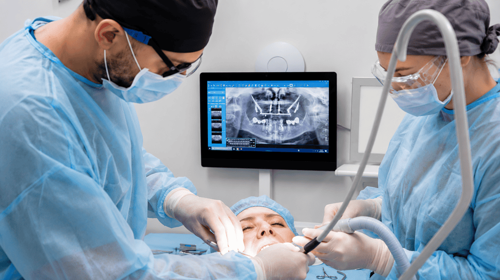 Dental surgeons performing a procedure with a patient in a clinical setting.