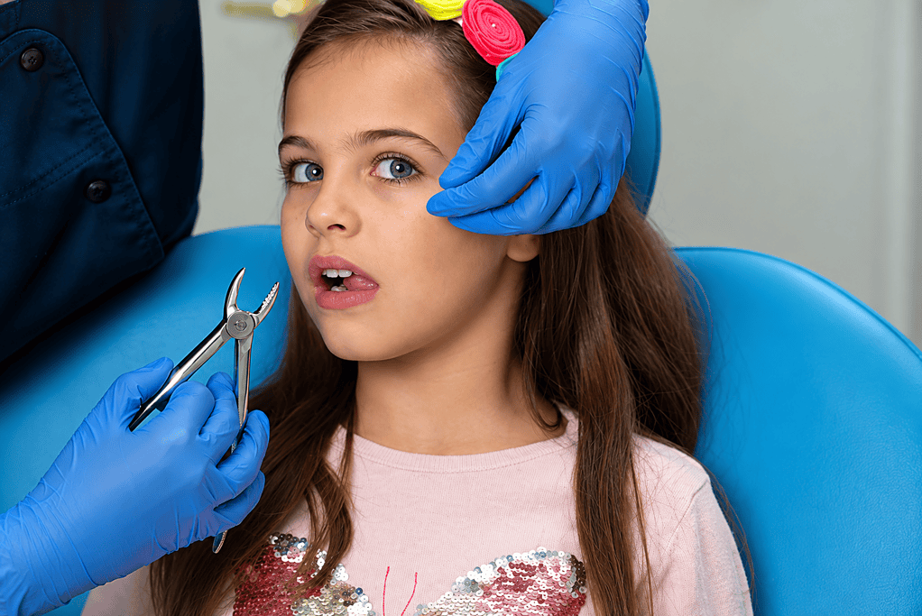 Young girl at the dentist receiving a checkup with dental tools.