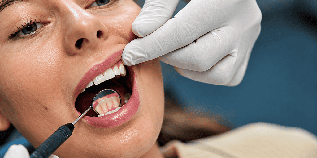 Woman receiving dental checkup with dental mirror and light.
