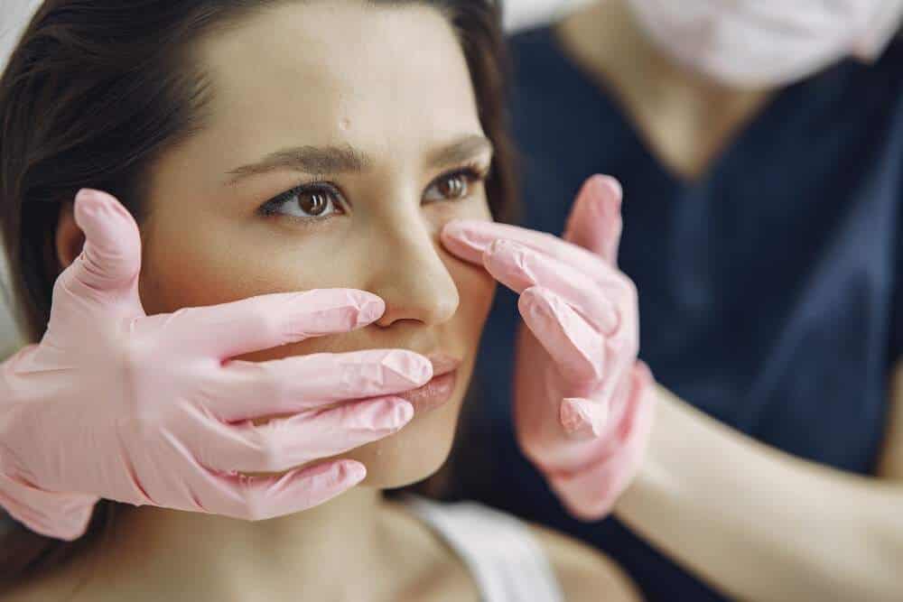 Woman receiving a plastic surgery consultation in Albania, close-up of face examination.