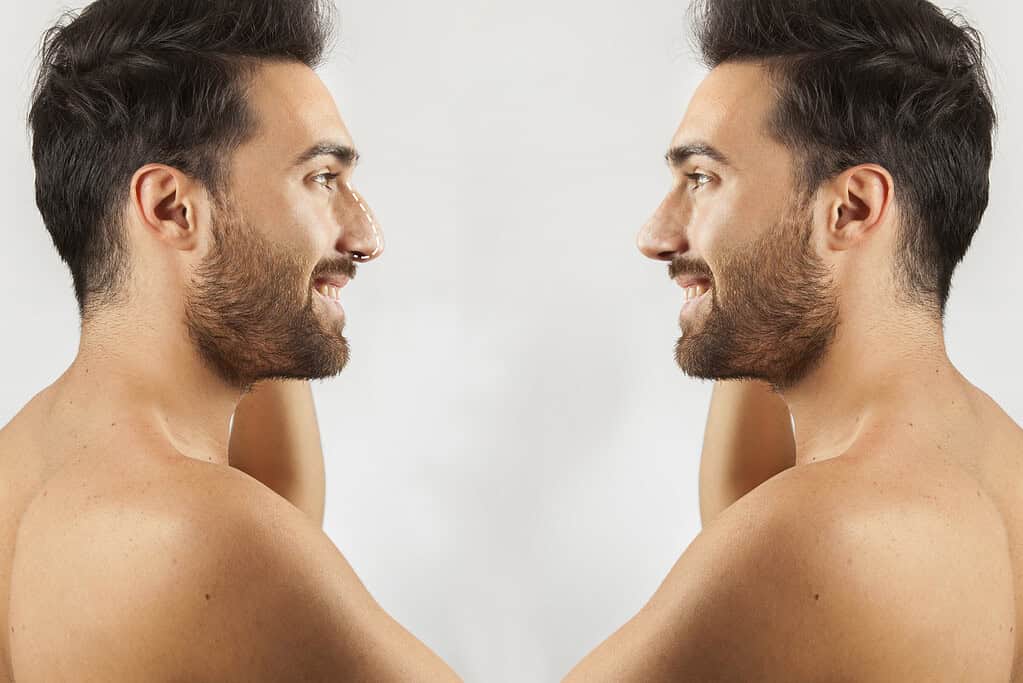 A man smiling at his reflection in a mirror, showcasing facial symmetry and confidence.