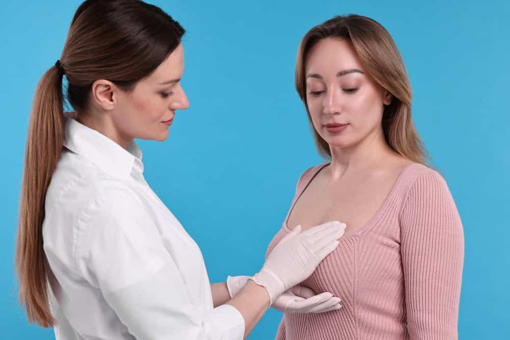 Doctor examining woman's breast for asymmetry assessment.